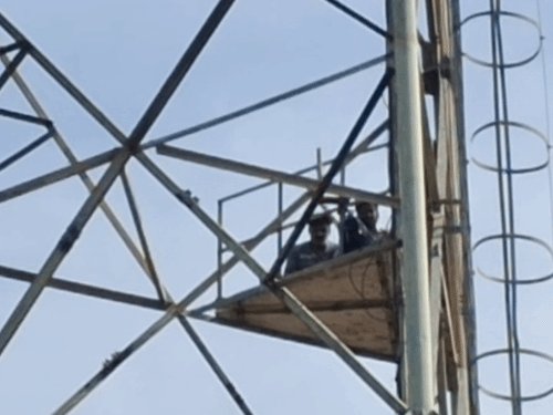 मंदिर कमेटी पर आरोप लगाकर दो युवक टावर पर चढ़े:बदायूं में 2 घंटे से नीचे नहीं उतर रहे, अधिकारी समझाने पहुंचे